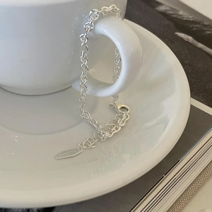 Macro shot of 925 silver link bracelet with lobster clasp on white coffee cup