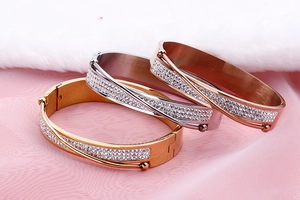 Detailed shot of stacked gold, silver, and rose gold bangles with cubic zirconia on silk