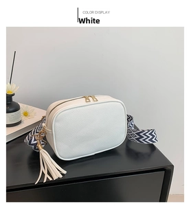 Dettaglio borsa bianca motivo litchi con tracolla geometrica e nappa in pelle