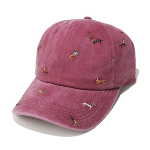 Detail of dog embroidery on washed burgundy corduroy baseball cap with vintage texture