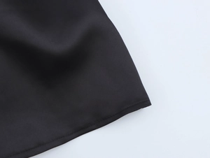 Detailed macro view of the black satin fabric texture and high-quality bottom hem stitching