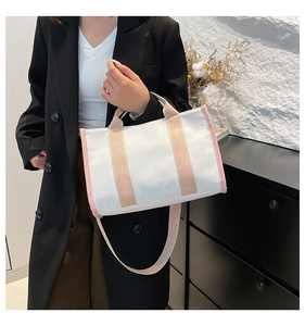 White canvas tote bag with pink handles and detachable strap shown in lifestyle setting