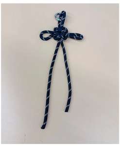 Close-up of black handmade woven Chinese knot keychain with white dots and silver ring