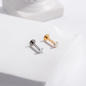 Macro view of gold and silver F136 titanium labret studs with white opal inlay