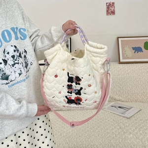 Detail of white heart-quilted tote bag with cute black cartoon dogs and pink straps