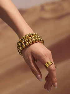 Detailed view of 18k gold plated multi-layer beaded heart bracelet and star engraved ring