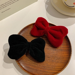 Close-up of red and black velvet bow hair clips for girls on a decorative wooden tray
