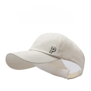 Detail of embroidered P letter on cream-white open top sun visor baseball cap