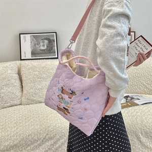 Detail of purple quilted tote with cartoon dachshund embroidery and woven handle