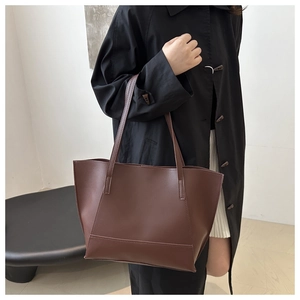 Deep brown matte leather tote bag styled with a black coat for an elegant commute look