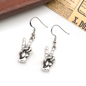 Antique silver hand gesture peace sign earrings with metal hooks on vintage background