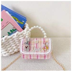 Detail of pink and white tweed girl's handbag with pearl handle and lace accents