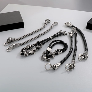 Detail of dragon, tiger, and anchor heads on black braided leather bracelets