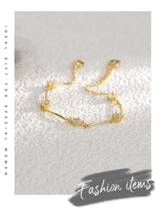 Detail of gold-plated brass bracelet with marquise-cut zircons on a white textured background