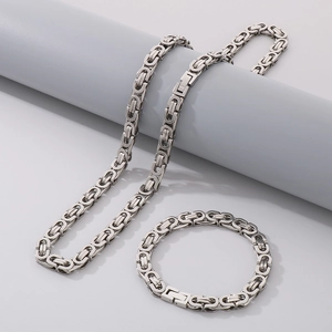 Close-up of silver stainless steel Byzantine chain necklace and bracelet set on grey display