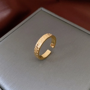 Close-up of golden vintage hammered ring on a grey jewelry box displaying metal texture