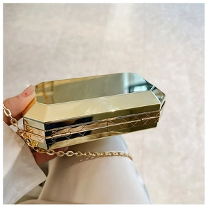 Close-up of golden geometric evening bag with faceted hard shell and metal chain