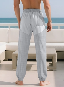 Detail of light grey joggers featuring unique patchwork texture and a tapered ankle cuff