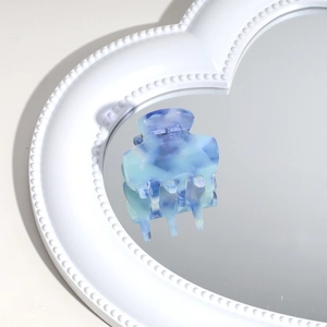 Macro view of blue marbled acetate hair claw clip reflecting on a heart-shaped mirror