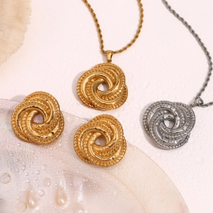 Flat lay of 18K gold and silver twisted knot earrings and necklaces with water droplets