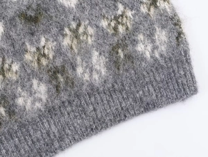 Close-up of jacquard knit texture with fuzzy grey wool blend and ribbed cuff details
