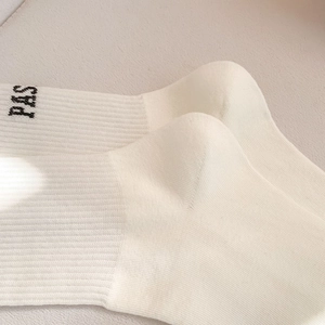 Detailed macro view of cream-colored cotton knit socks with ribbing and PAS letter design