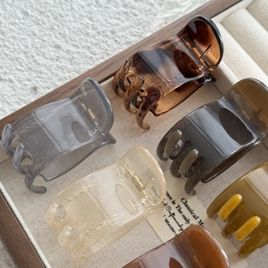 Minimalist 5cm hair claws in amber and cream tones arranged in a wooden box