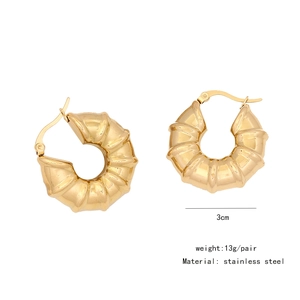 Detailed view of 3cm golden spiral textured stainless steel hoop earrings on white background