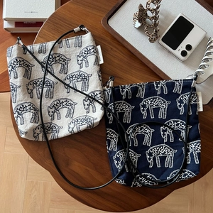 Flat lay of small canvas crossbody bags with sheep embroidery on a wooden table