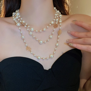 Detail of multi-layer pearl necklace with golden rose charms on a female model