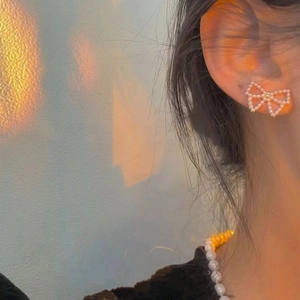 Close-up of elegant pearl bow earrings featuring delicate openwork butterfly design