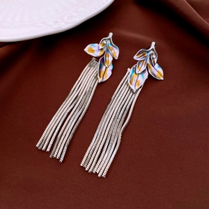 Detailed shot of vintage silver leaf tassel earrings with purple petals on brown fabric