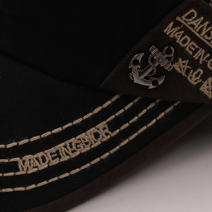 Detail of contrast stitching, side embroidery, and vintage metal anchor on baseball cap