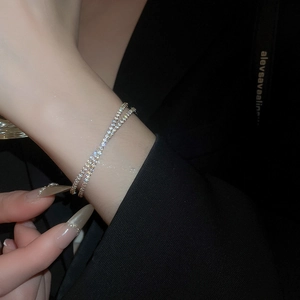 Détail d'un bracelet double rangée en zircon argenté porté au poignet sur un blazer noir