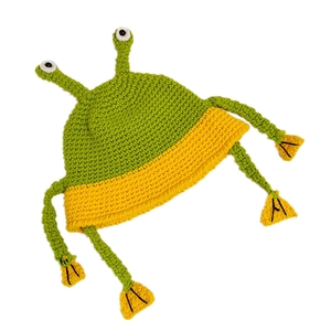 Handmade knitted frog bucket hat with big eyes and hanging legs on a white background