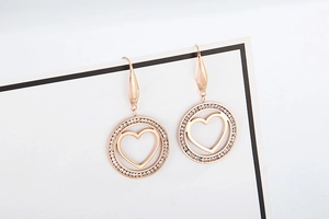 Macro view of rose gold heart pendant earrings with sparkling diamond circle detail