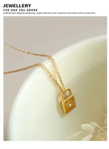 Close-up of a gold padlock pendant with starburst engraving and a tiny zircon on a fine chain