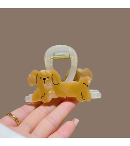 Detailed view of a yellow cartoon puppy hair claw clip made of acetate with a metal spring