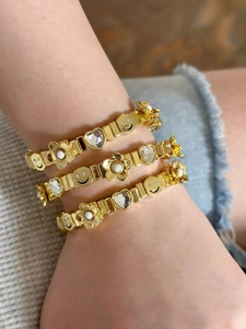 Close-up of golden elastic bracelets with sparkling heart charms and smiling face motifs