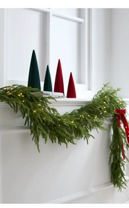 Detail of green PE Christmas garland with warm LED lights and red ribbons on white mantel