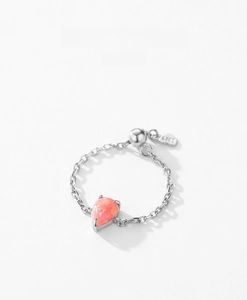 Macro detail of S925 sterling silver chain ring with pear-cut pink opal and logo tag