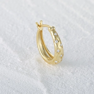 Detail of gold-plated silver hoop earring with star pattern and zircon inlay