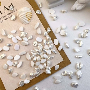 Macro detail of baroque irregular pearl nail charms with pearlescent resin textures