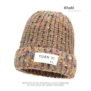 Detail of khaki chunky knit beanie featuring multi-color specks and white brand label