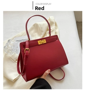 Close-up of red trapezoid handbag featuring gold rotary lock and smooth faux leather finish