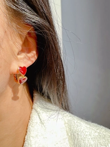 Close-up of model wearing red enamel double heart earrings with gold metal rings
