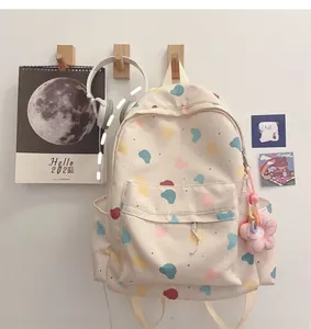 Detail of off-white canvas backpack with cute cartoon prints and plush flower keychain