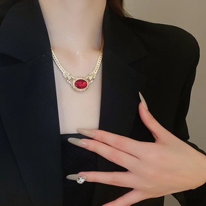 Close-up of vintage gold necklace with oval red stone and crystals on a model