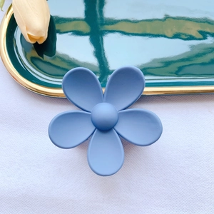 Detailed macro view of the matte pastel blue flower hair claw clip on a luxury tray