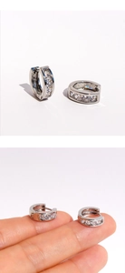 Detailed view of silver hoop earrings with cubic zirconia shown in hand for scale
